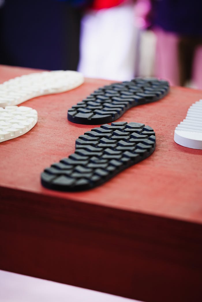 Close-up of textured rubber shoe soles displayed on a red surface with a blurred background.