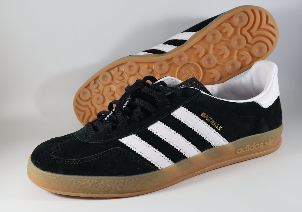 Pair of Adidas Gazelle sneakers in black and white with gum sole displayed prominently.